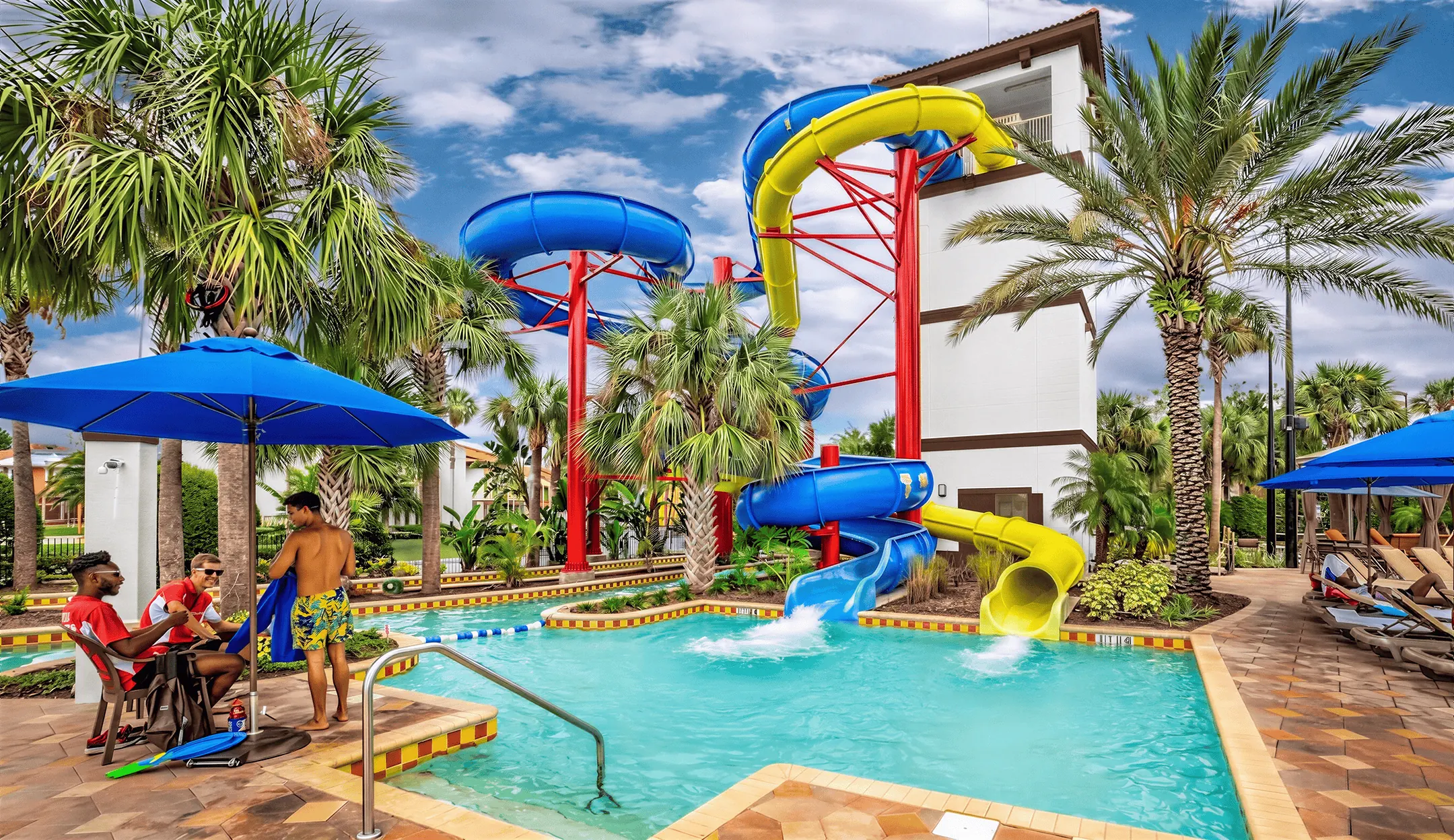 Twin water slides with blue and yellow tubes towering over the pool