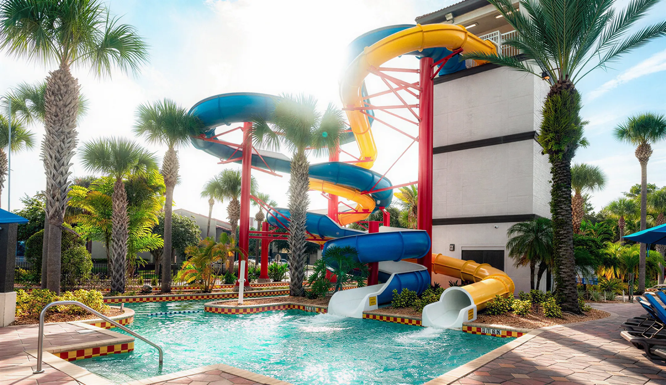 Spiral and straight chute water slides framed by palm trees